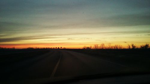 Road amidst silhouette landscape against sky during sunset