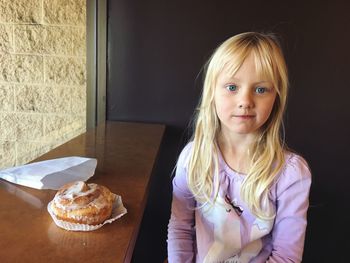 Portrait of cute girl sitting by sweet food at table