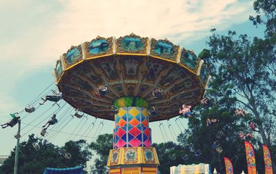 Low angle view of chain swing ride against sky