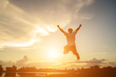 Rear view of silhouette man jumping against sky during sunset