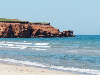 Rock formations on beach against clear sky