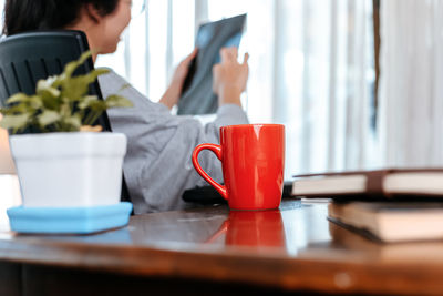 Close-up of coffee mug on desk with businesswoman in background