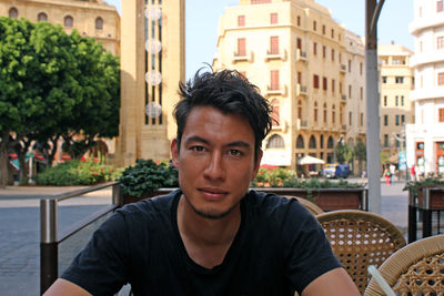 Portrait of young man sitting in city