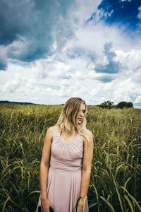 Young woman standing in farm against sky