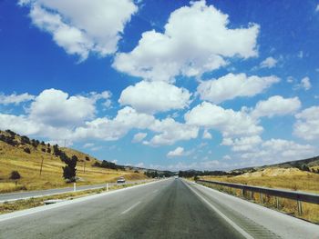 Scenic view of road amidst field against sky