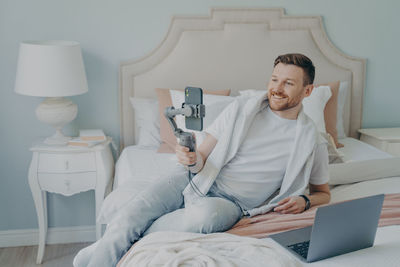 Man using mobile phone while sitting on bed