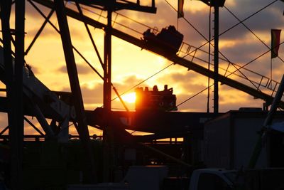 Silhouette of machinery against sky during sunset