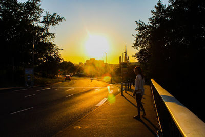 Man standing on road at sunset