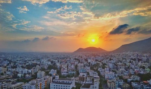 Cityscape by sea against sky during sunset