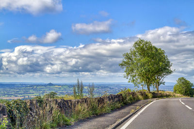 Empty road by sea against sky