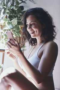 Side view of smiling woman using mobile phone at home