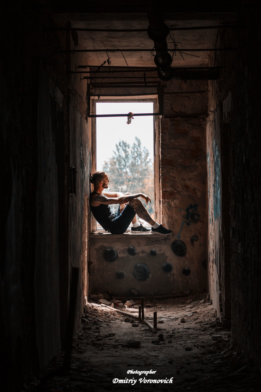 WOMAN SITTING IN CORRIDOR OF BUILDING