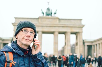 Portrait of man talking on phone against brandenburg gate