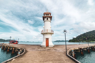 Lighthouse by sea against sky