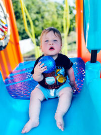 Portrait of cute boy playing with toy against blue background