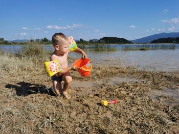 Shirtless boy playing at lakeshore