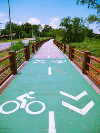 Text on footpath by road against sky