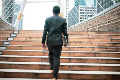 Rear view of man walking on staircase of building