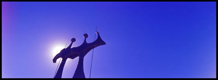 Low angle view of silhouette birds against clear blue sky