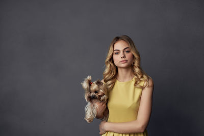 Portrait of teenage girl with dog against gray background