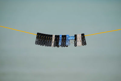 Low angle view of clothespins hanging on rope against sky