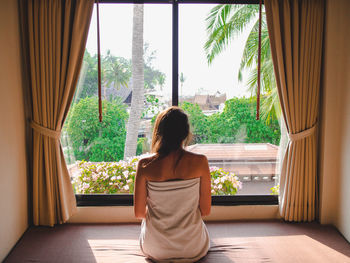 Rear view of woman looking through window 