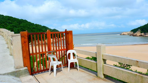 Chairs and table at beach against sky