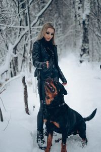 Full length of woman with dog in snow