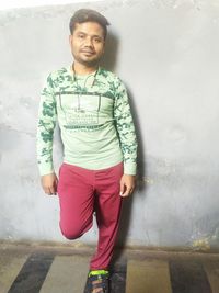 Portrait of young man standing against wall