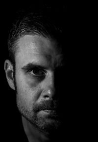 Close-up portrait of young man against black background