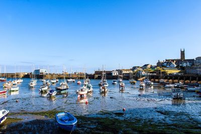 Boats moored at harbor against sky