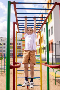 The boy does sports on horizontal bars of different colors