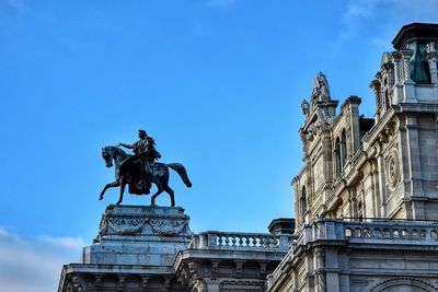 Statue by historic building against sky