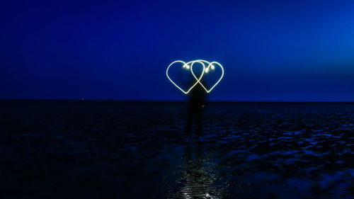 Light painting on sea against clear sky at night