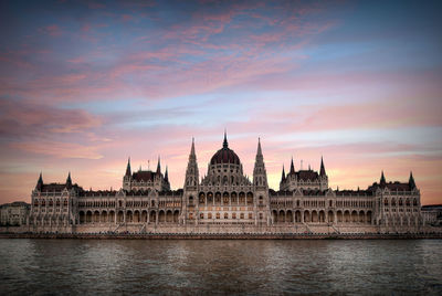 View of river against sky during sunset in city