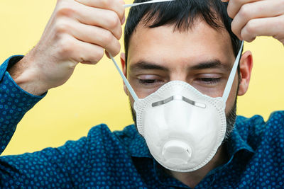 Young man wearing a mask on a yellow background