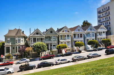 Cars by houses against sky in city