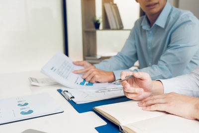 Midsection of man holding paper at table