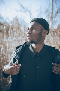 Portrait of young man standing against sky