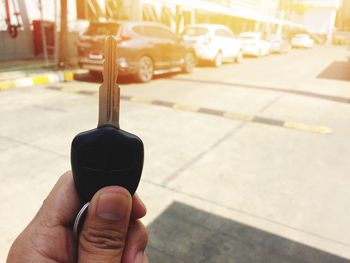 Cropped hand holding car key on road