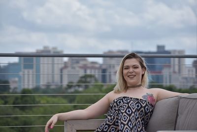 Portrait of smiling young woman against railing