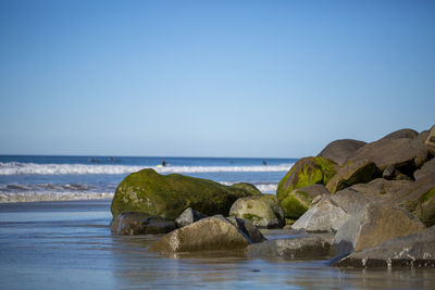 Rocks on beach against clear sky