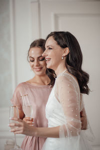 Bridesmaid and bride holding champagne flute