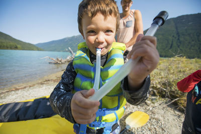 Cute boy plays with air tube for inflating boats during paddling trip