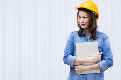 Young woman wearing hat standing against wall