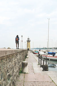 Woman on pier with lighthouse against sky at desenzano del garda