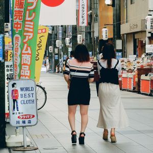 Rear view of women standing on street in city