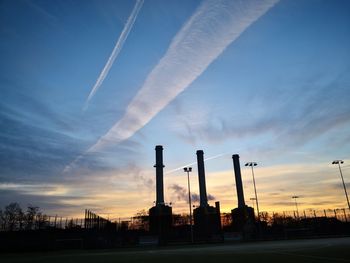 Low angle view of silhouette factory against sky during sunset