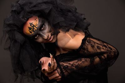 Portrait of smiling young woman with painted face against black background