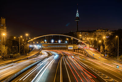 Light trails on road in city against sky at night